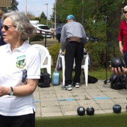 Two members of Willowdale Lawn Bowling Club are looking at something off camera during opening day at Willowdale Lawn Bowling Club. 