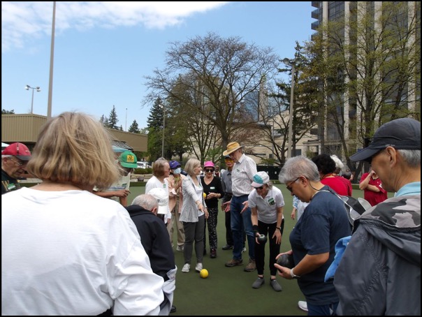 Ann is explaining something while everyone looks on at the Willowdale Lawn Bowling Club. 