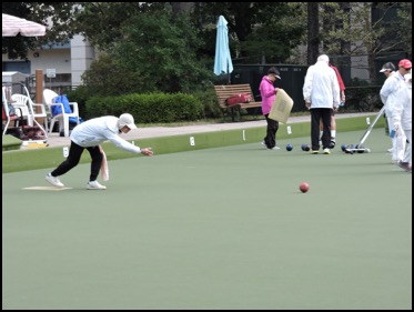 Tournament bowler delivering while others rake