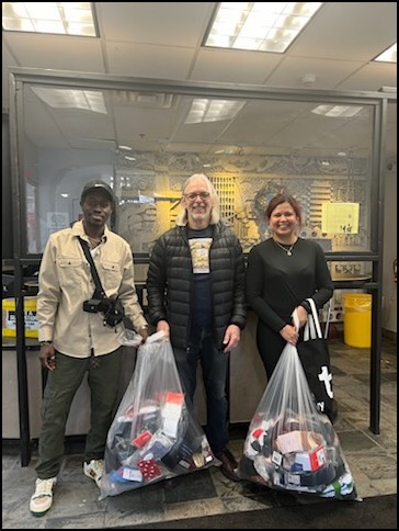 Board member Eric Bergman (centre) delivers two bags of socks to the Willowdale Welcome Centre. 